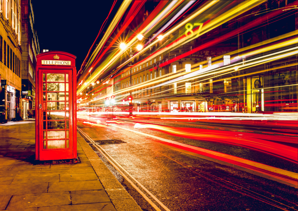 Red telephone box on a busy London street at night
