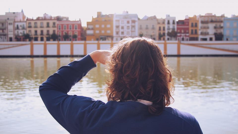 Woman looking at colourful houses along the river in Seville, Spain